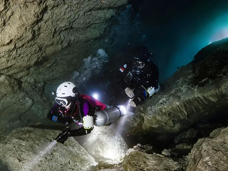 Deux plongeurs explorent une grotte sous-marine éclairée par des lampes
