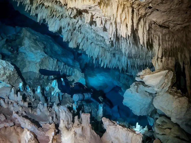 Plongeur explore une grotte sous-marine illuminée avec des stalactites