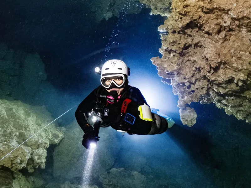 Plongeur éclairant une grotte sous-marine avec une lampe torche