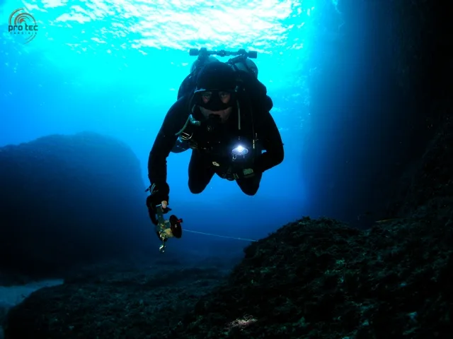 Plongeur avec appareil photo sous l'eau, lumière naturelle et artificielle