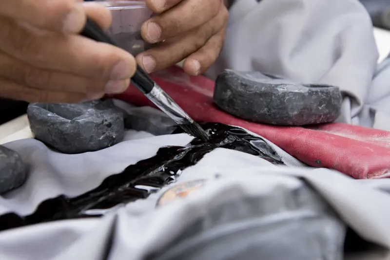 Mains appliquant un produit noir sur une combinaison de plongée