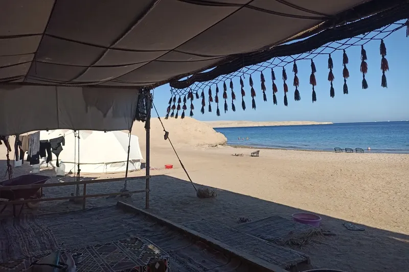 Vue d'une plage de sable avec des tentes et un abri ombragé