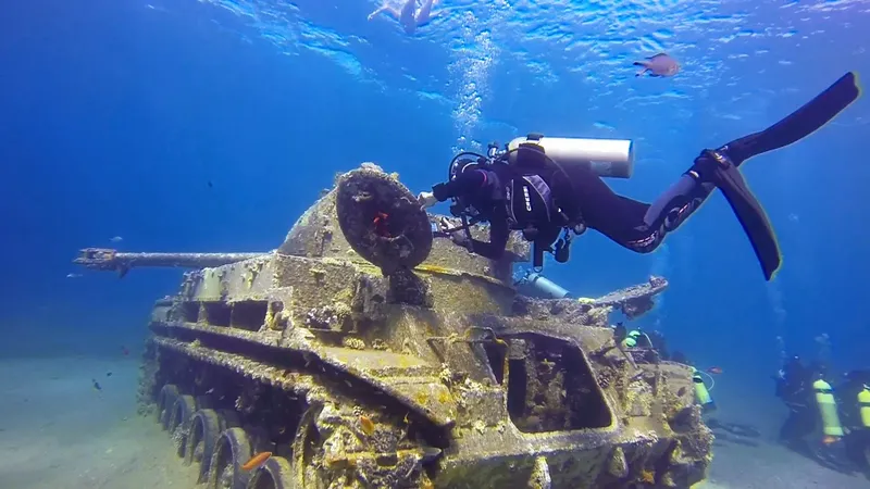 Plongeur explorant un char d'assaut coulé au fond de la mer
