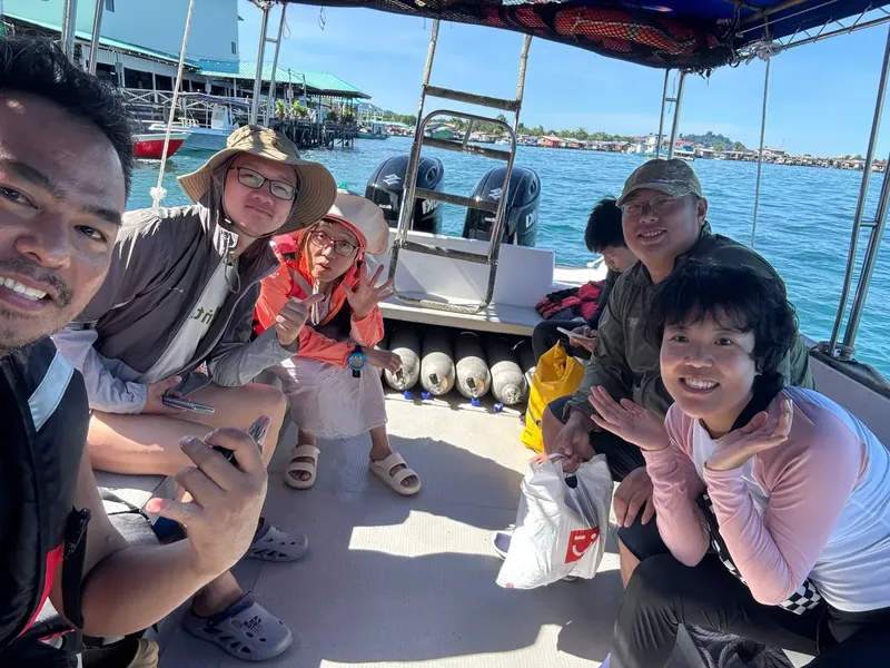 Groupe de personnes souriantes à bord d'un bateau de plongée en mer