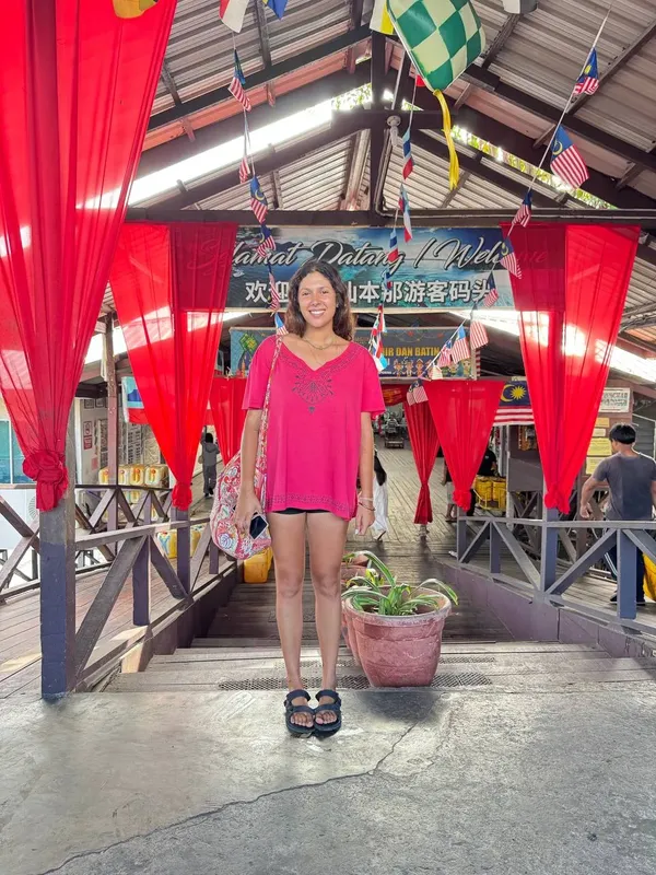 Femme souriante devant une structure couverte avec des drapeaux et du texte