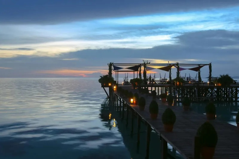 Ponton en bois illuminé au coucher du soleil sur la mer