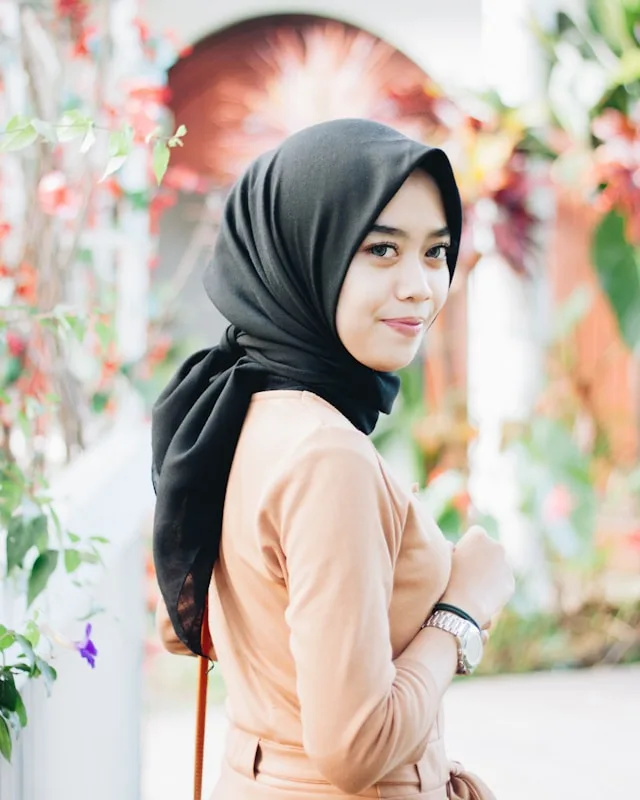 Jeune femme souriante portant un foulard noir et une tunique beige