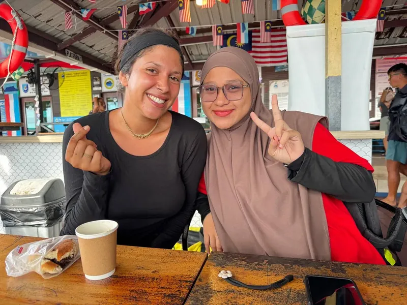 Deux femmes souriantes font des signes de la main devant un comptoir