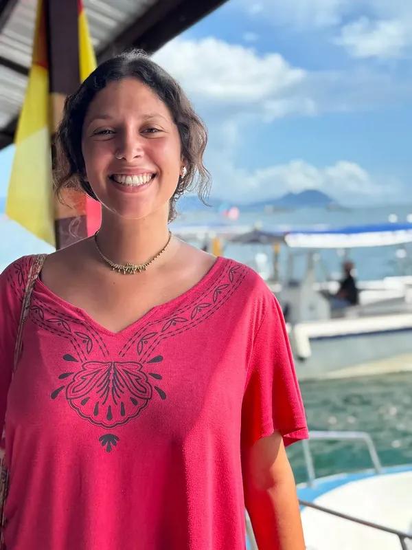 Femme souriante en tenue estivale devant un bateau amarré