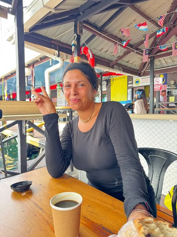 Femme souriante assise à une table avec une boisson et nourriture