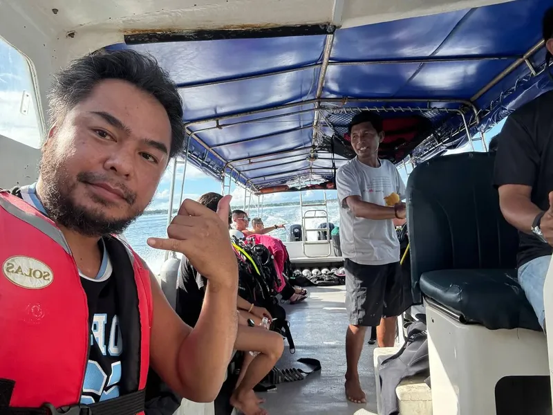 Groupe de plongeurs souriants sur un bateau en direction d'un site