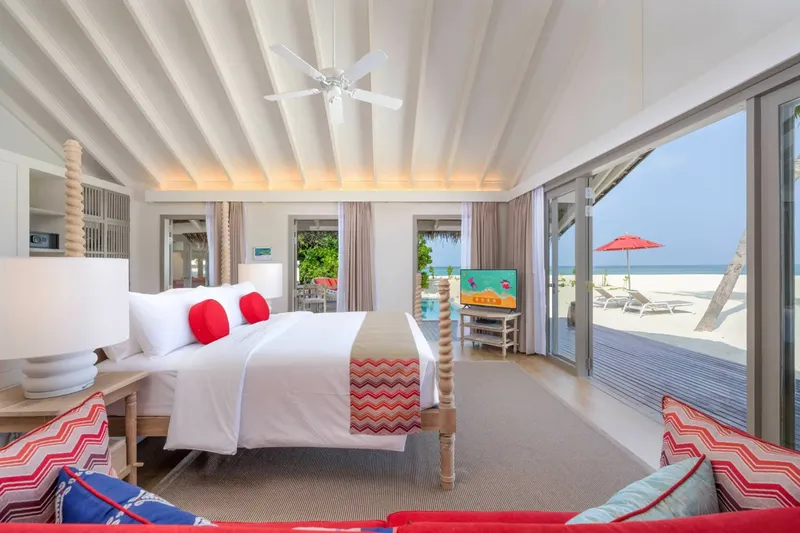 Chambre lumineuse avec lit king size donnant sur une plage tropicale