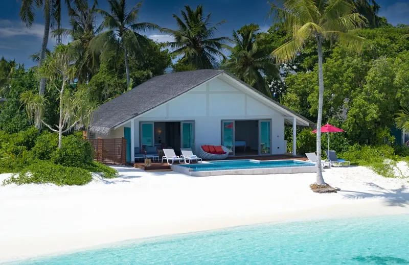 Villa blanche sur plage de sable blanc avec piscine et végétation tropicale