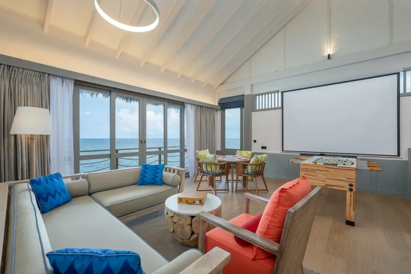Intérieur lumineux avec canapés, table, vue sur mer et baby-foot