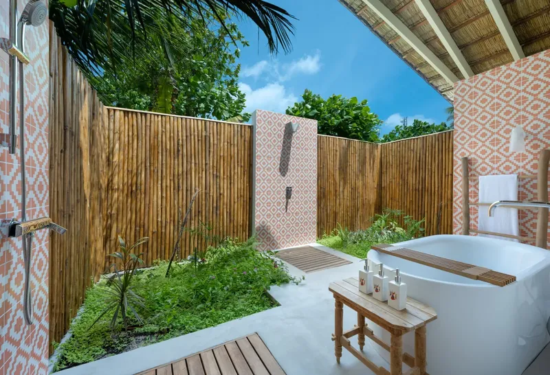 Espace extérieur avec douche, baignoire et végétation luxuriante, ambiance relaxante