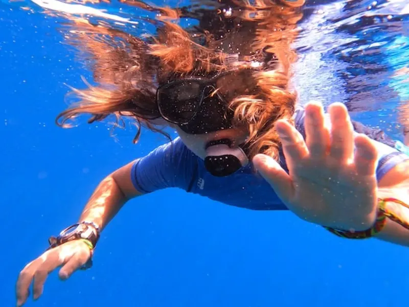 Plongeuse souriante avec masque et tuba, cheveux flottants dans l'eau