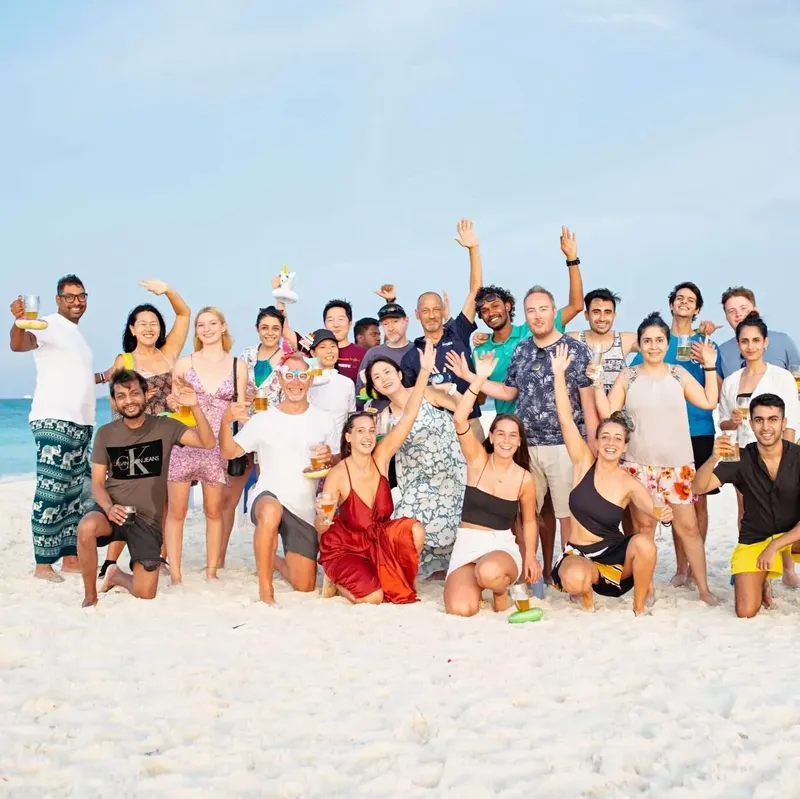 Groupe de personnes souriantes sur une plage de sable blanc