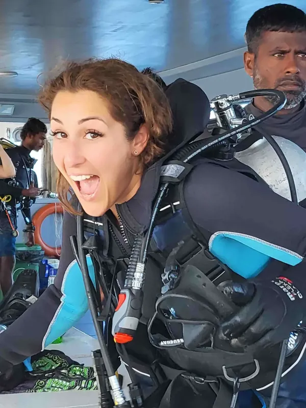 Plongeuse souriante avec son équipement complet à bord d'un bateau