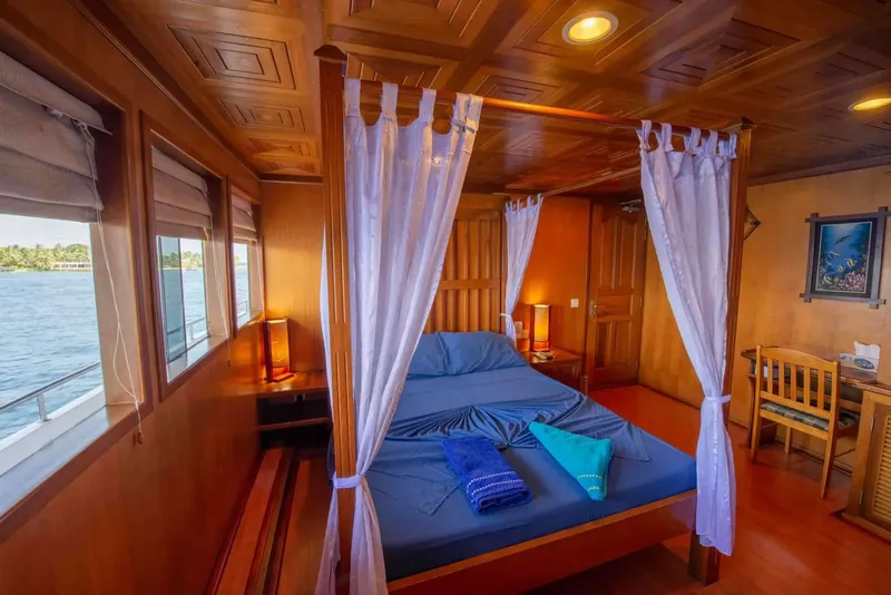 Intérieur de cabine de bateau avec lit à baldaquin et vue mer