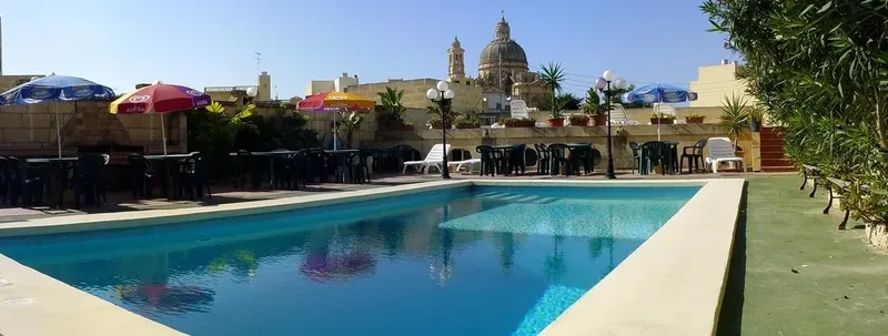 Piscine et terrasse avec parasols, vue sur un village et une église
