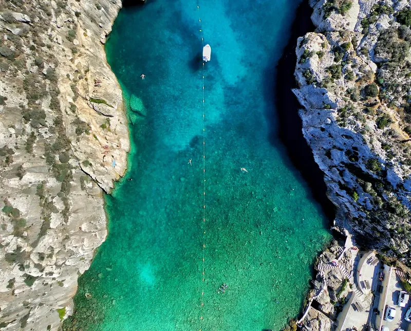 Vue aérienne d'une crique turquoise avec un bateau et des nageurs