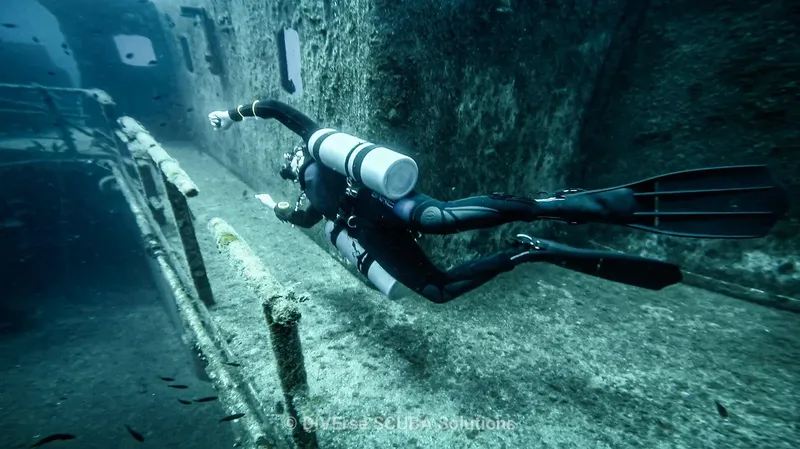 Plongeur explore une épave sous-marine avec visibilité et lumière bleutée