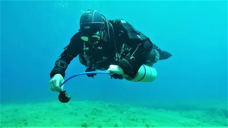 Plongeur en combinaison noire manipule un appareil sous-marin en pleine eau
