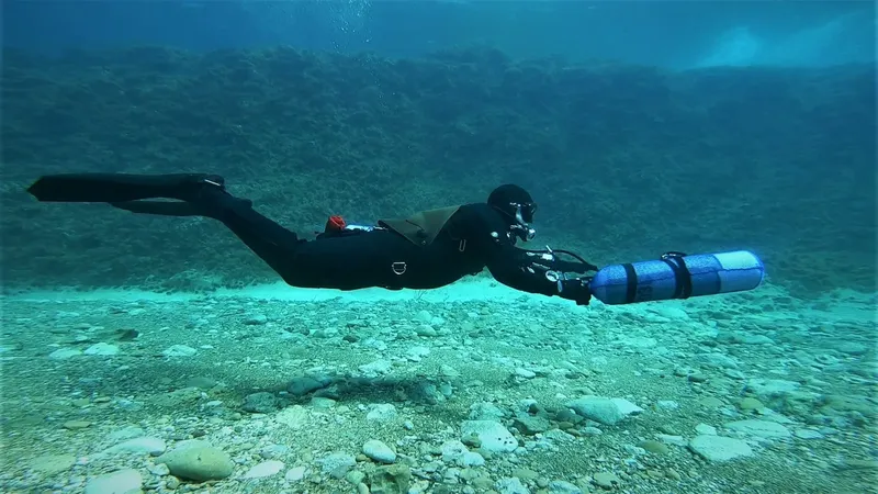Plongeur en combinaison nageant sous l'eau avec son équipement complet