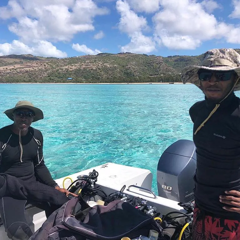 Deux plongeurs souriants sur un bateau en mer turquoise