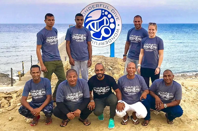 Groupe de personnes souriantes posant sur une plage ensoleillée