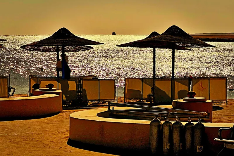 Terrasse avec parasols, bouteilles de plongée et mer scintillante au loin