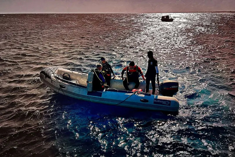 Plongeurs préparant une sortie en mer à bord d'un semi-rigide bleu