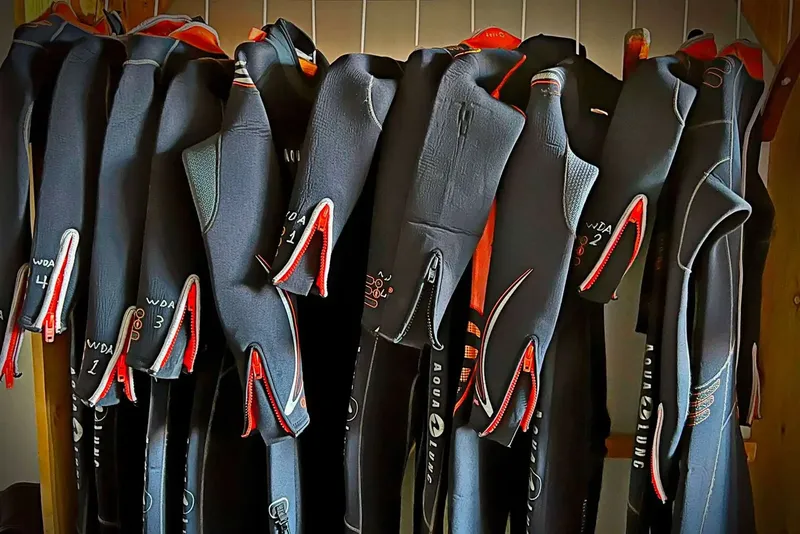 Rangée de combinaisons de plongée noires et rouges suspendues à des cintres