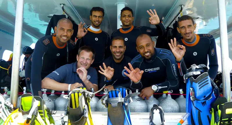Groupe de plongeurs souriants, équipés, prêts pour une sortie en mer
