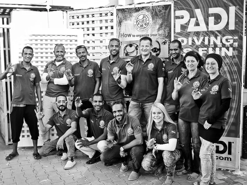 Groupe de personnes souriantes devant une bannière PADI et un mur