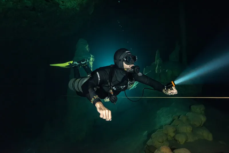 Plongeur en apnée explore une grotte sous-marine éclairée par une lampe