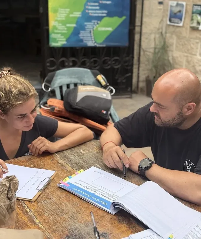 Deux personnes discutent et prennent des notes à une table en extérieur