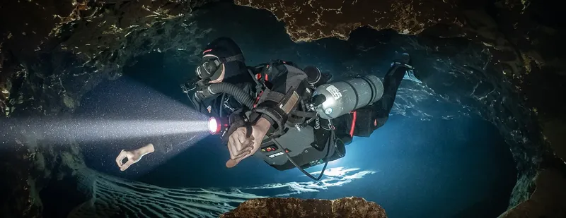 Plongeur explore une grotte sous-marine avec une lumière puissante