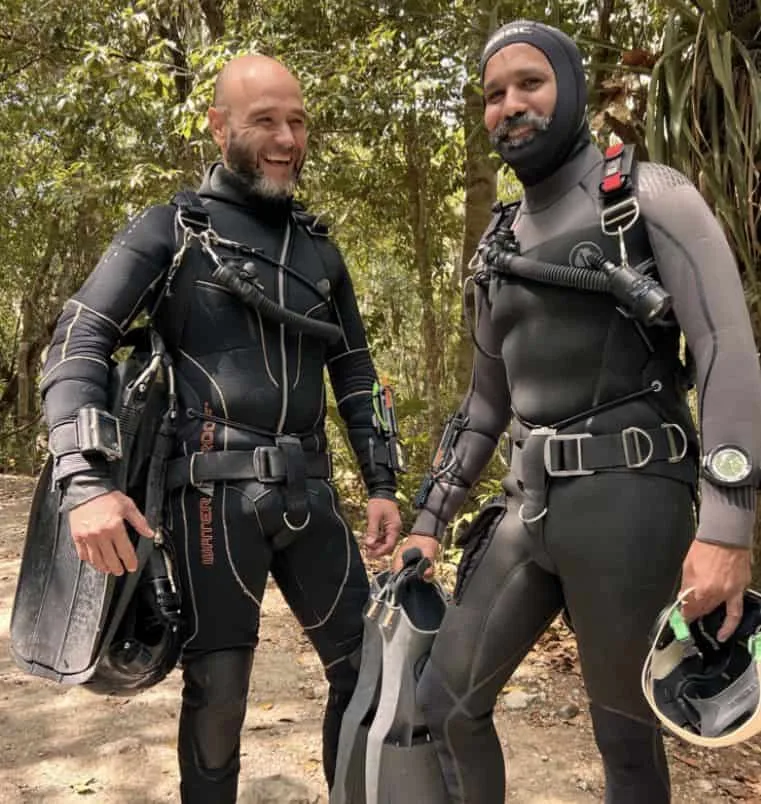 Deux plongeurs souriants équipés de combinaisons et de palmes se préparent
