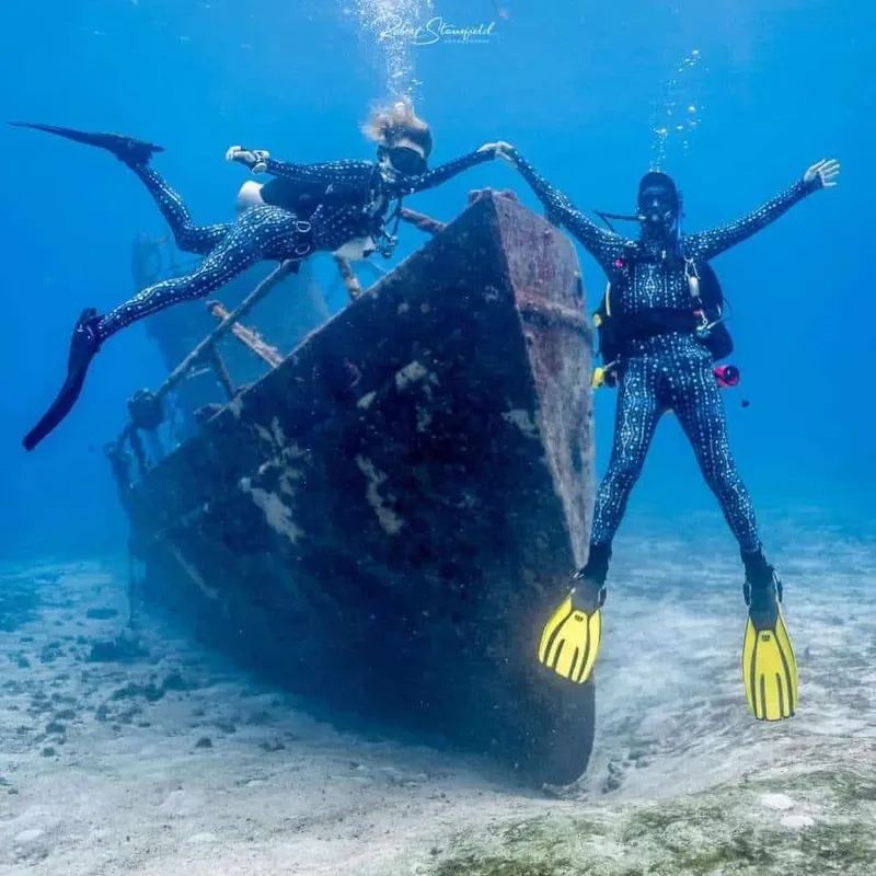Deux plongeuses s'étirent devant l'épave d'un bateau immergé
