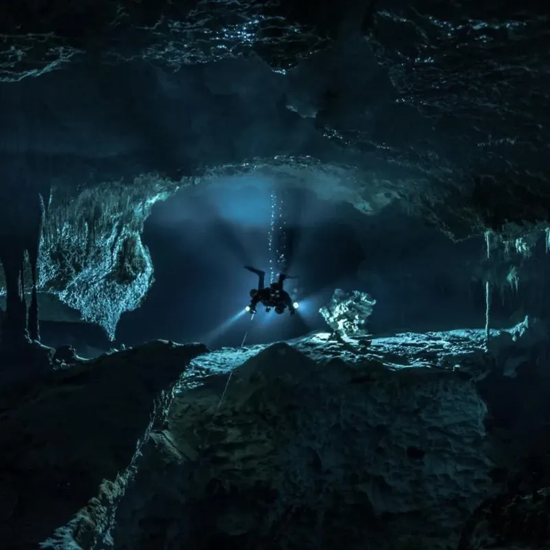 Plongeur explorant une grotte sous-marine éclairée par sa lampe torche
