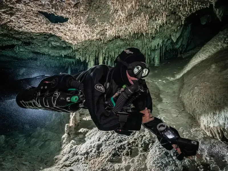 Plongeur explore une grotte sous-marine avec stalactites et stalagmites