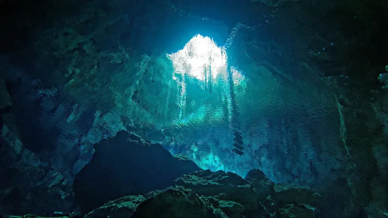 Vue sous-marine d'une grotte rocheuse avec un faisceau lumineux descendant