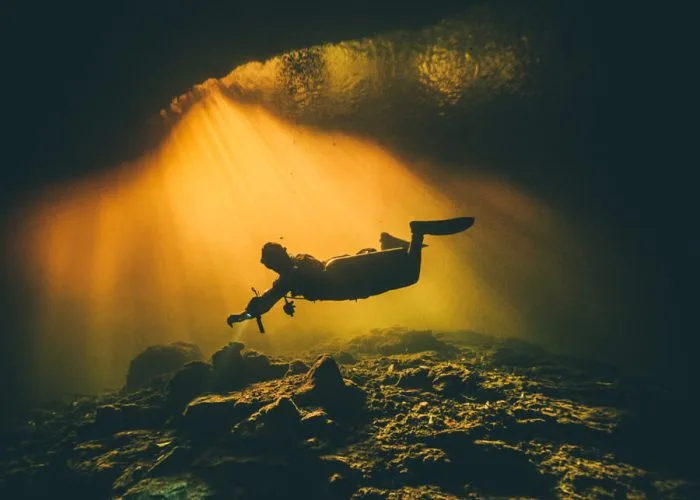 Plongeur silhouette dans une grotte sous-marine éclairée par le soleil