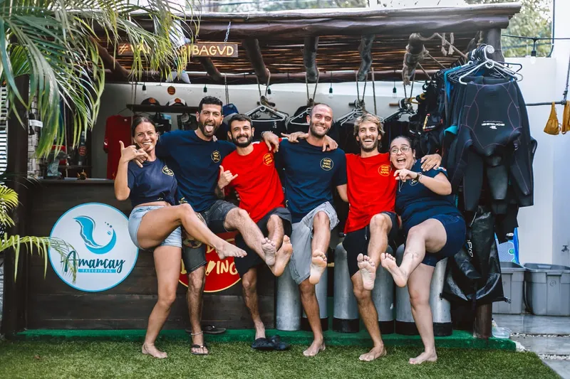 Equipe souriante du centre de plongée posant devant le matériel