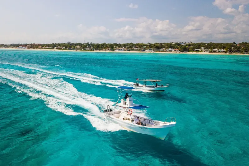 Deux bateaux de plongée naviguent sur une mer turquoise ensoleillée