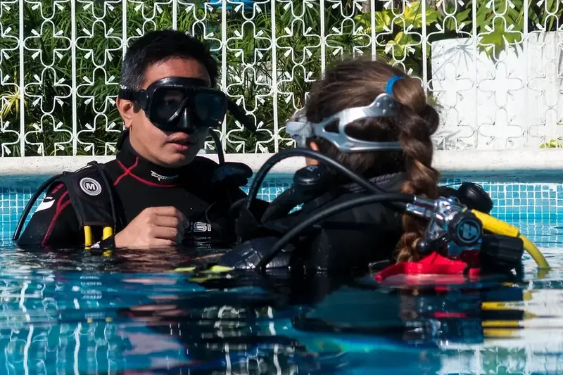 Deux plongeurs en formation dans une piscine, équipement complet visible