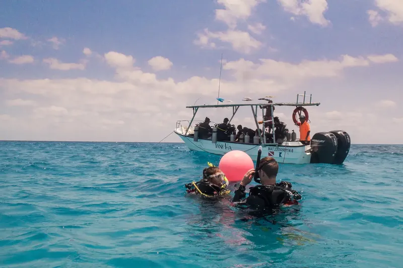 Plongeurs près d'un bateau de plongée en mer, ciel bleu nuageux