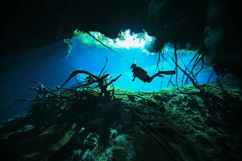 Plongeur silhouette sombre explorant une grotte sous-marine éclairée par le soleil