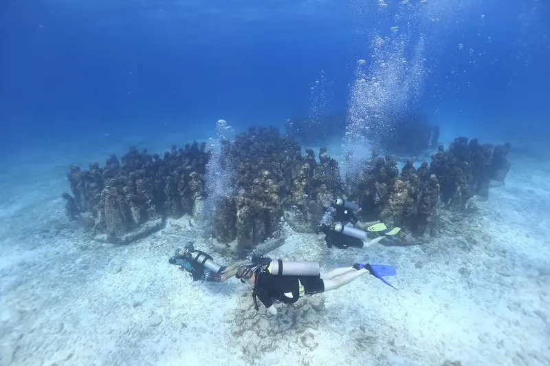 Deux plongeurs explorent une sculpture sous-marine dans un environnement clair
